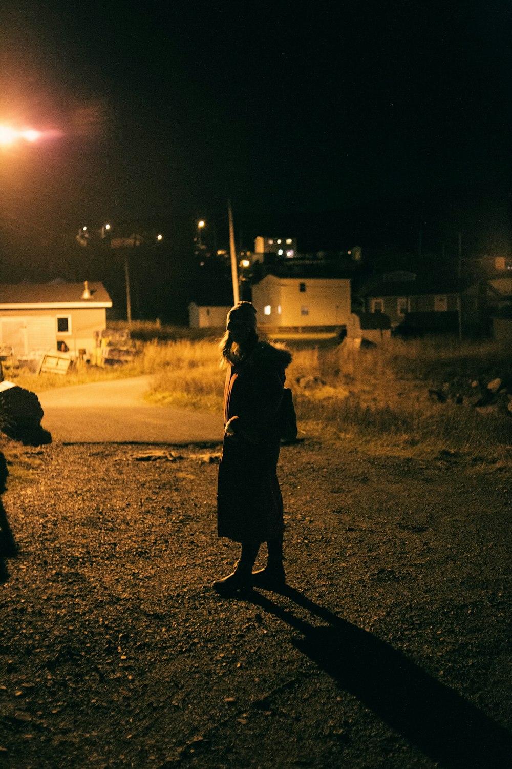 a woman standing on a dirt road at night