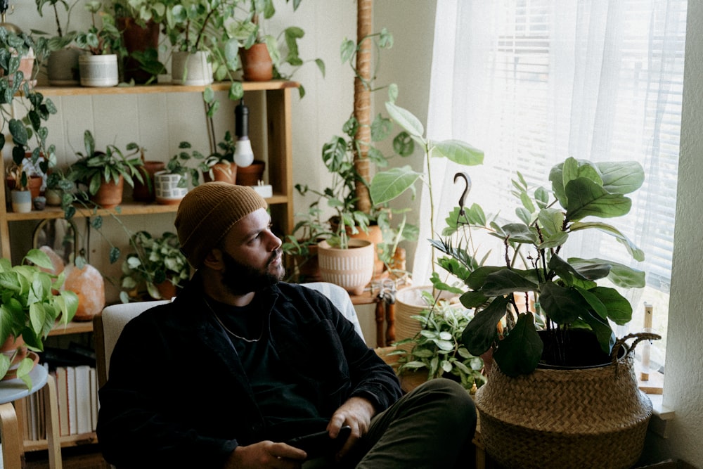 a man sitting in a chair next to a potted plant