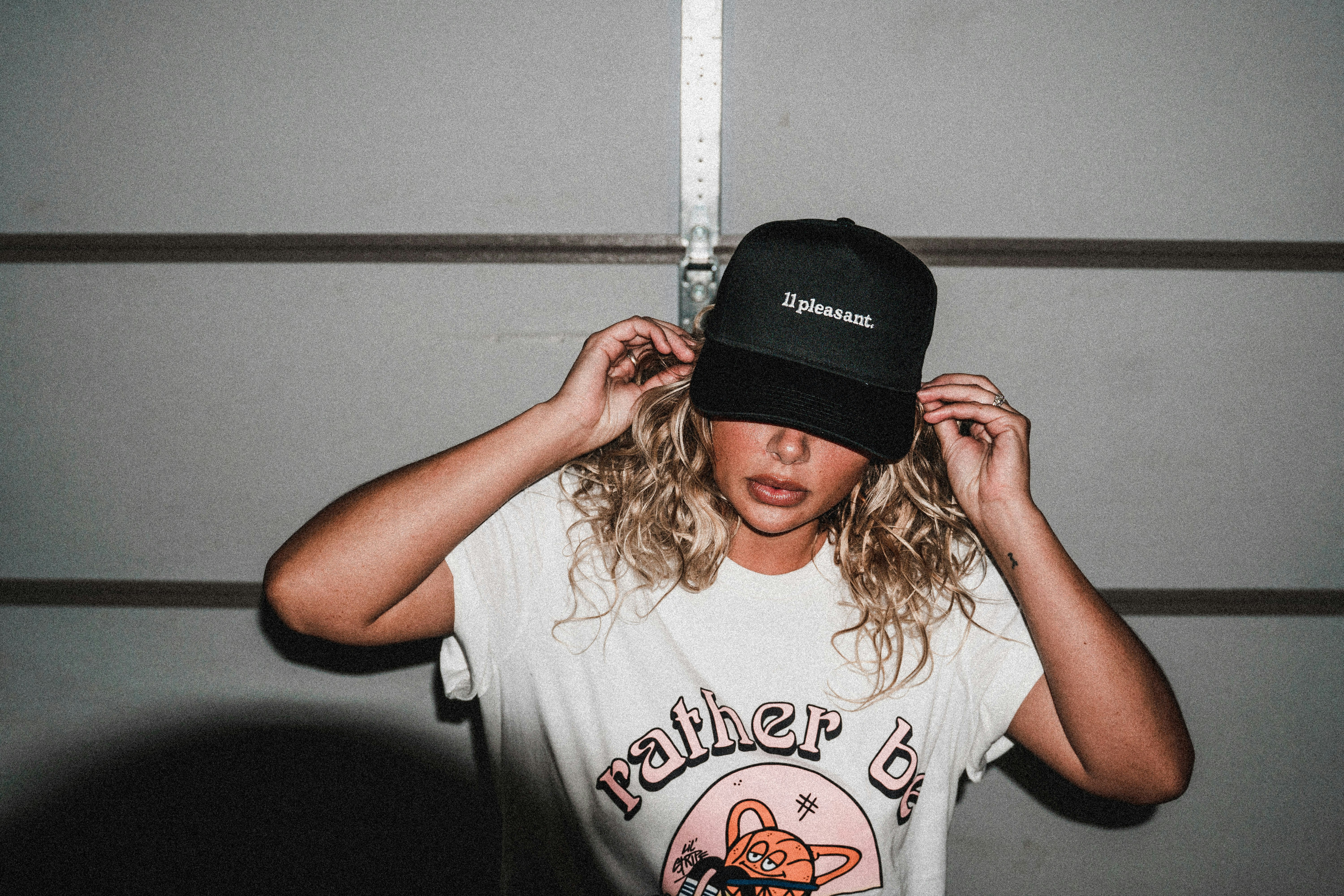 a woman wearing a hat and measuring her hair