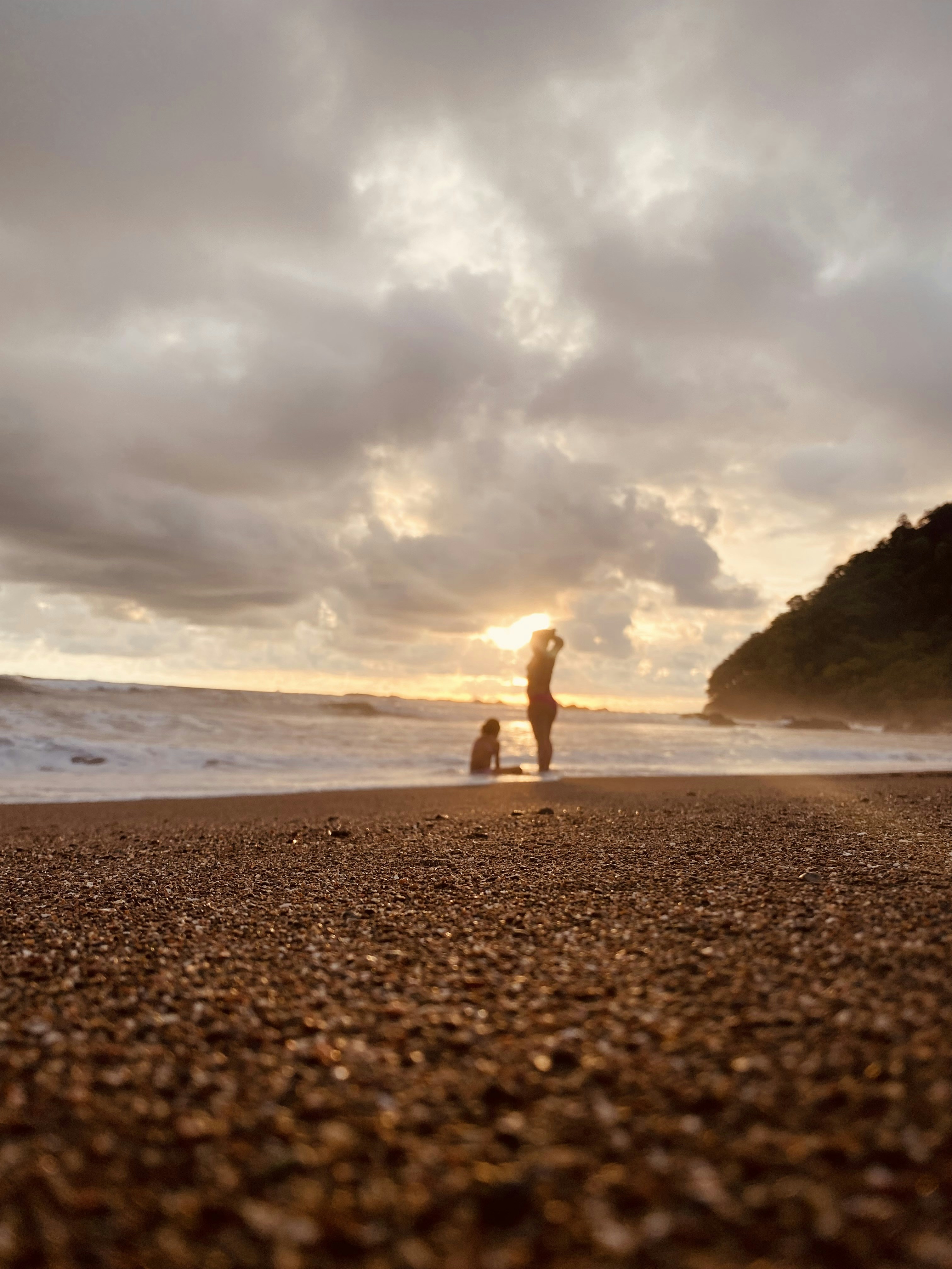 a couple of people standing on top of a sandy beach