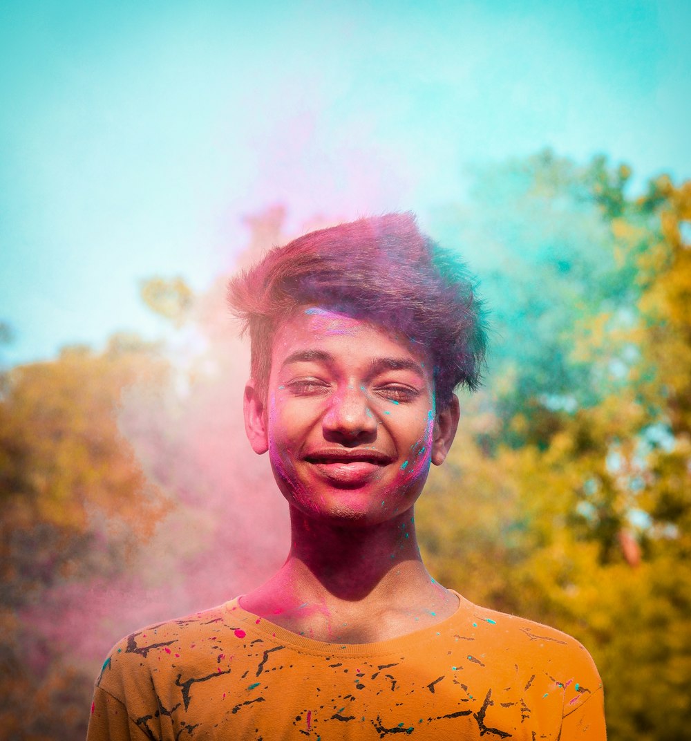 a young man is smiling and covered in colored powder