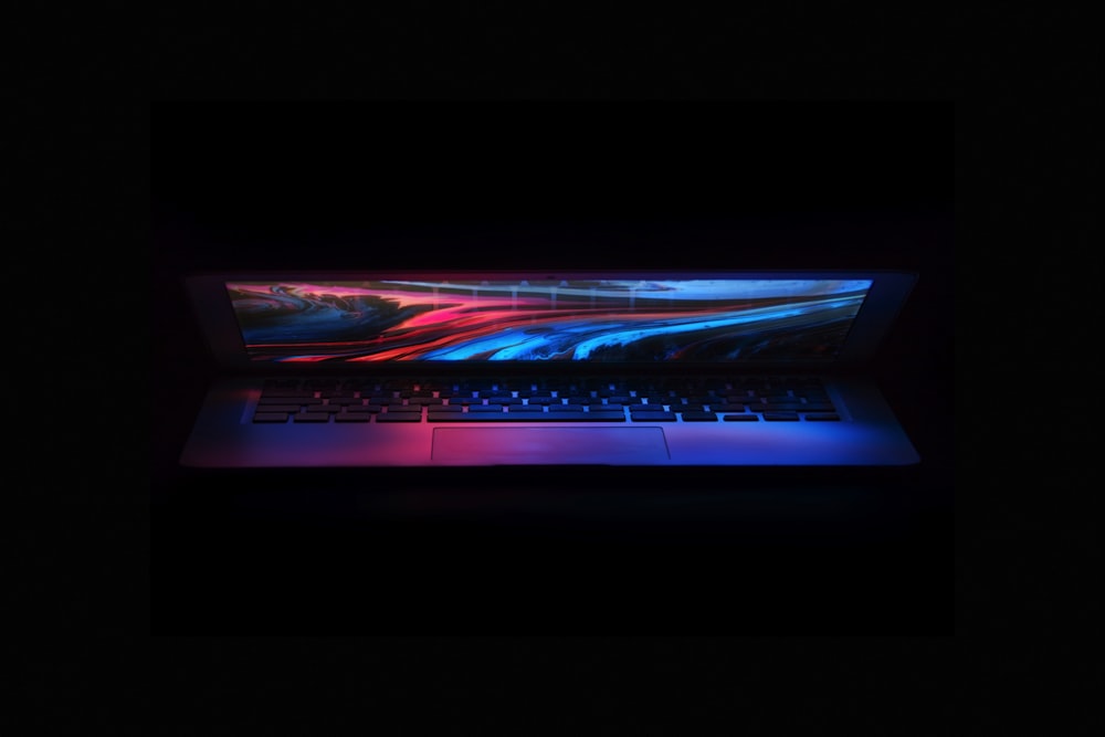 a laptop in the dark with a colorful background