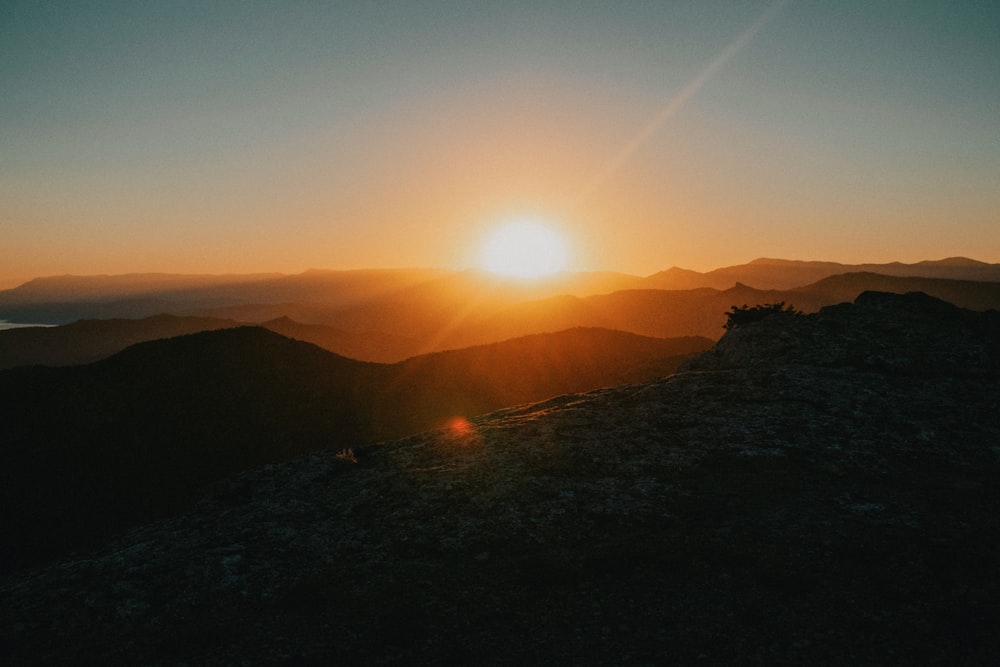 the sun is setting over a mountain range