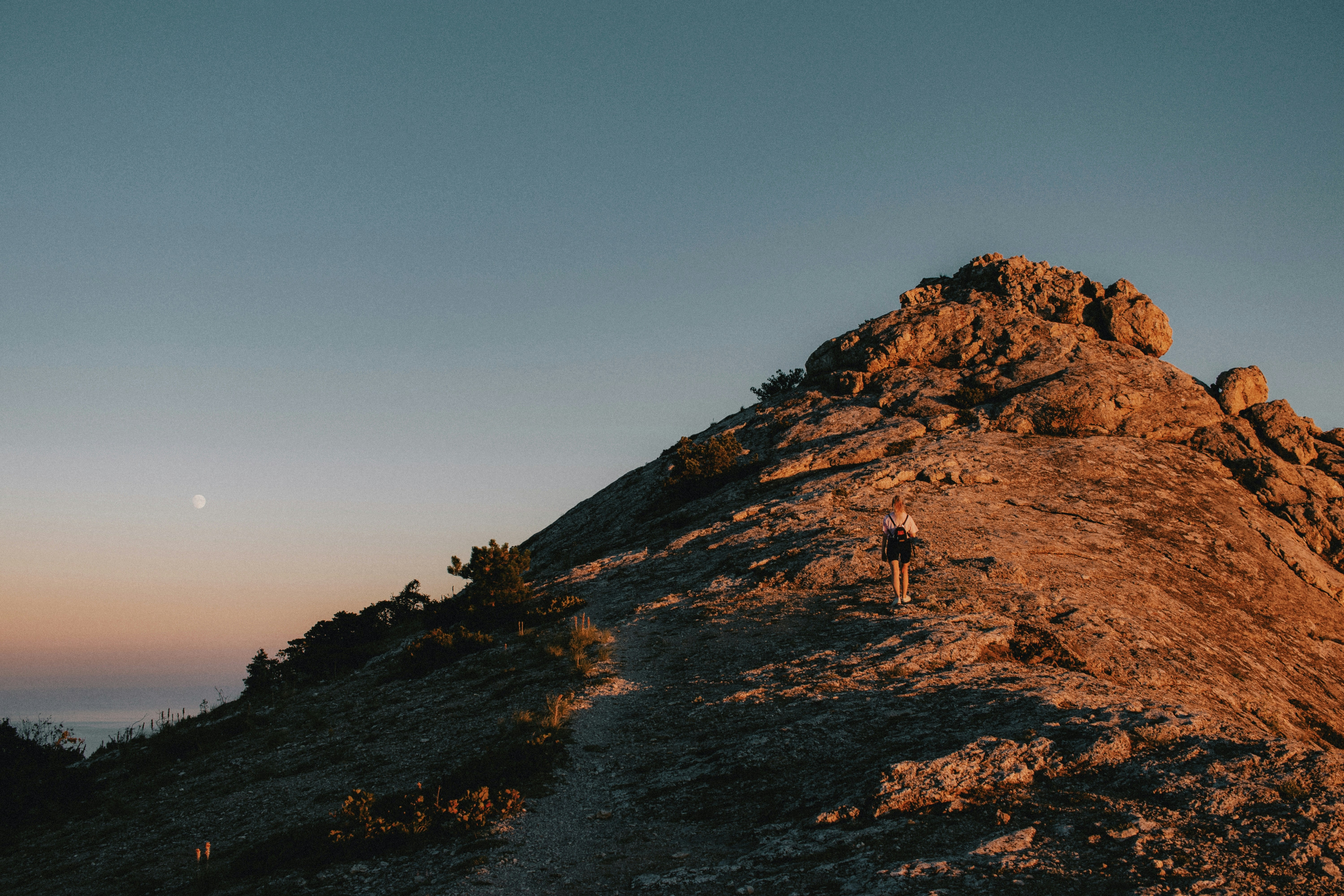 a person hiking up a rocky mountain at sunset, climbing to the top of the Sokol mountain