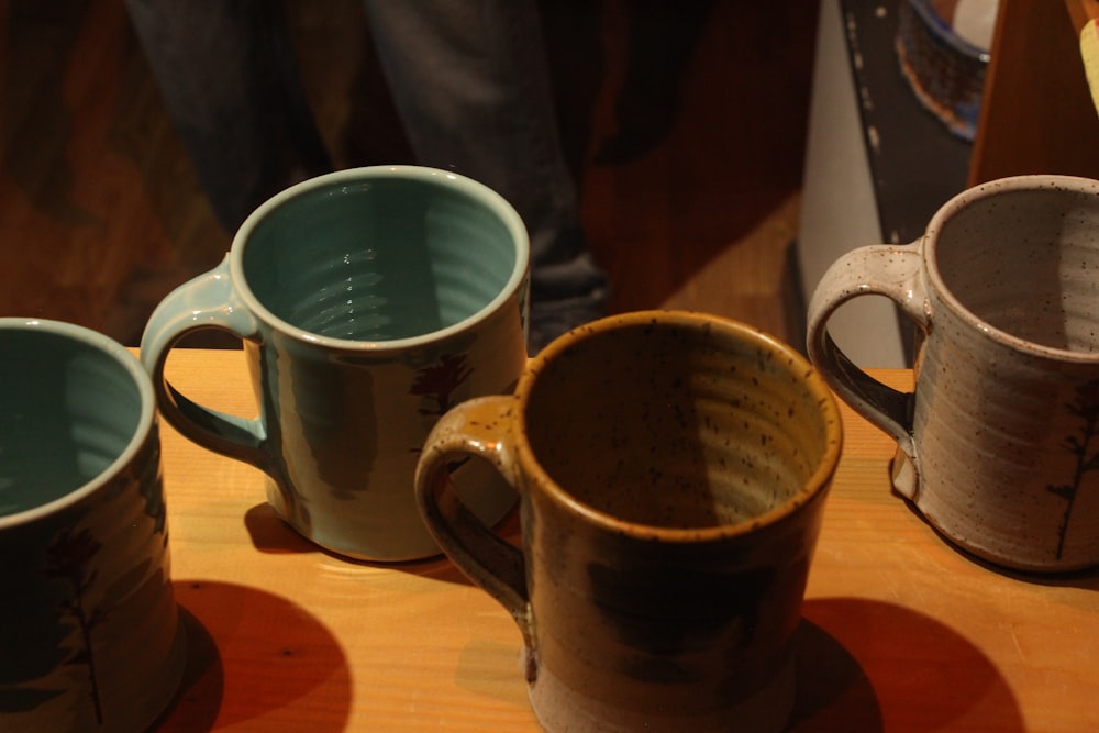 three coffee cups sitting on top of a wooden table