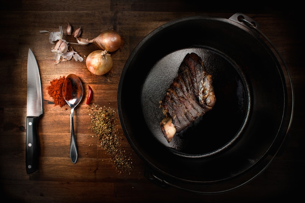 a steak is cooking in a skillet on a wooden table