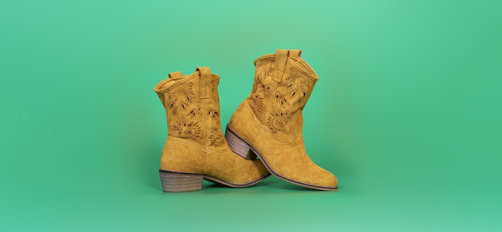 a pair of yellow cowboy boots on a green background