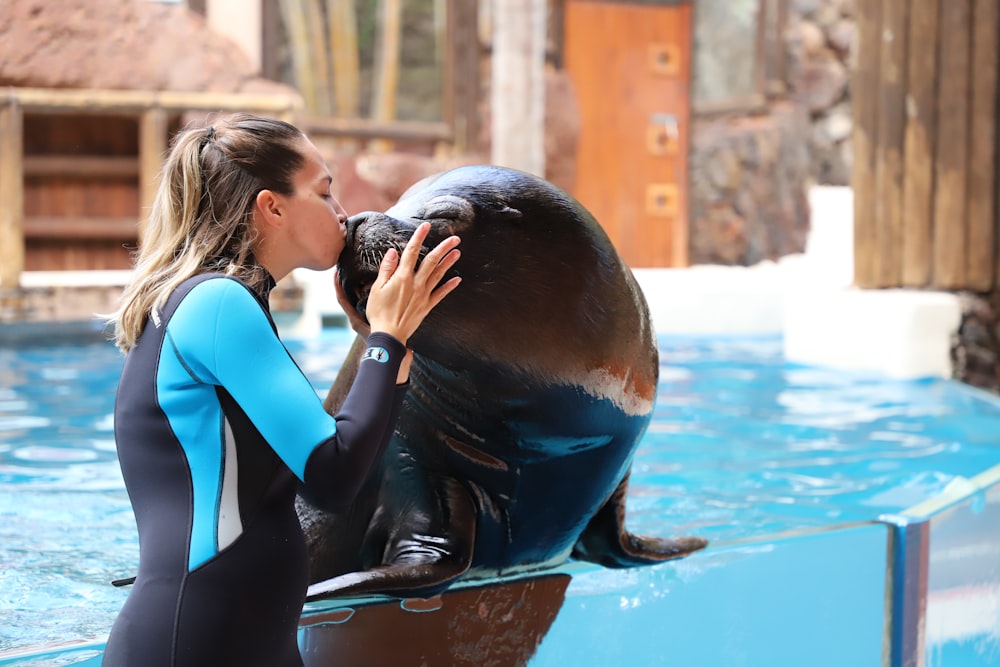 a woman kissing a seal in a pool