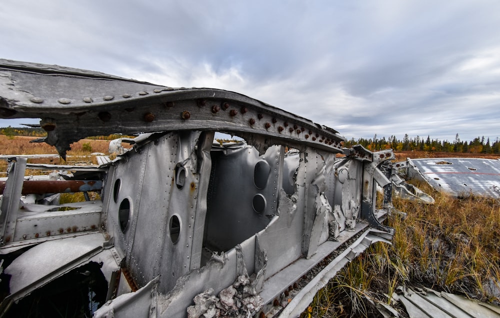 a rusted out train car sitting on top of a grass covered field