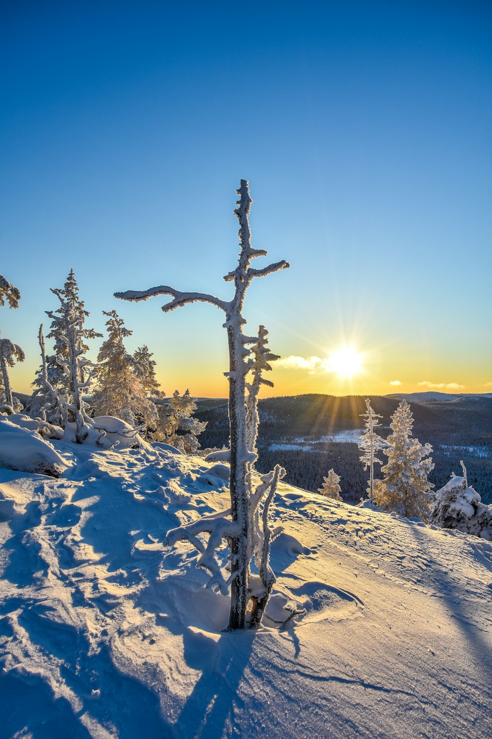 the sun is setting over a snowy mountain