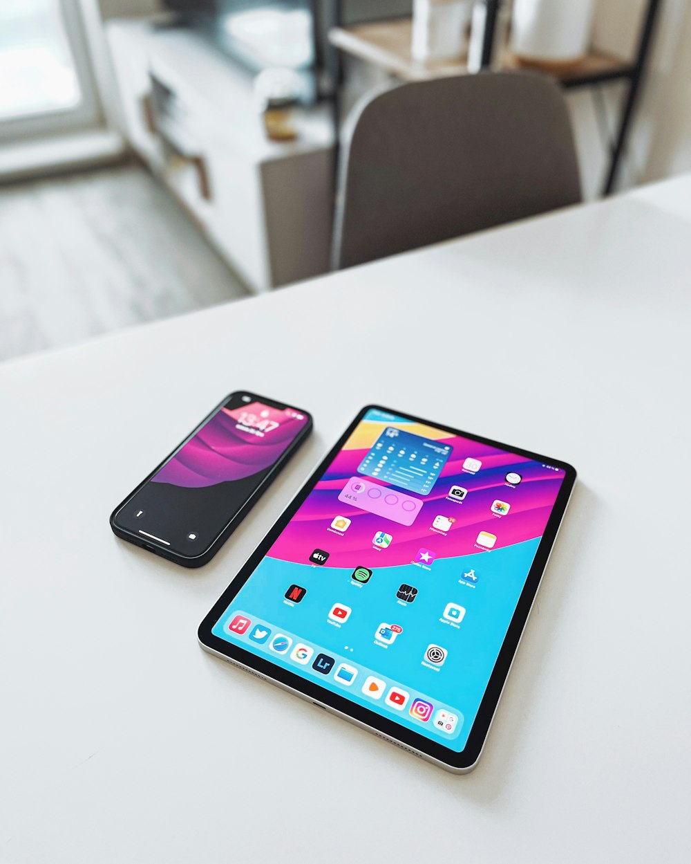 two cell phones sitting on top of a white table