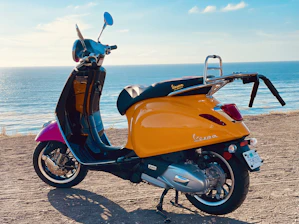 A vibrant yellow scooter ready for a coastal ride with the ocean in the background.