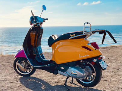 A vibrant yellow scooter ready for a coastal ride with the ocean in the background.