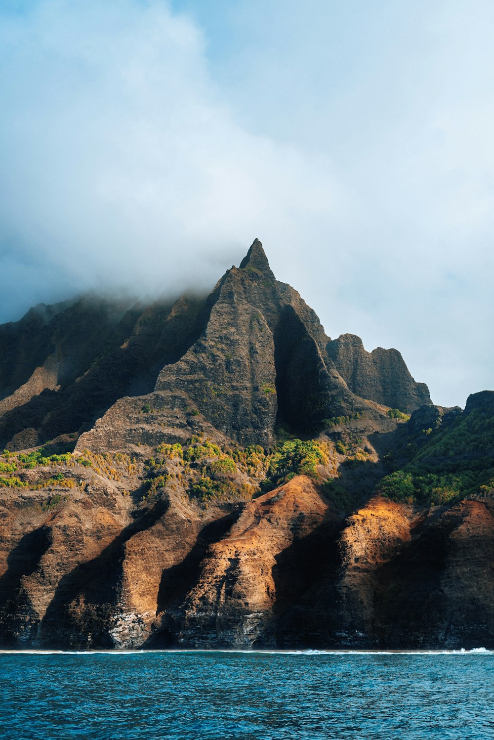 a very tall mountain sitting on the side of a body of water