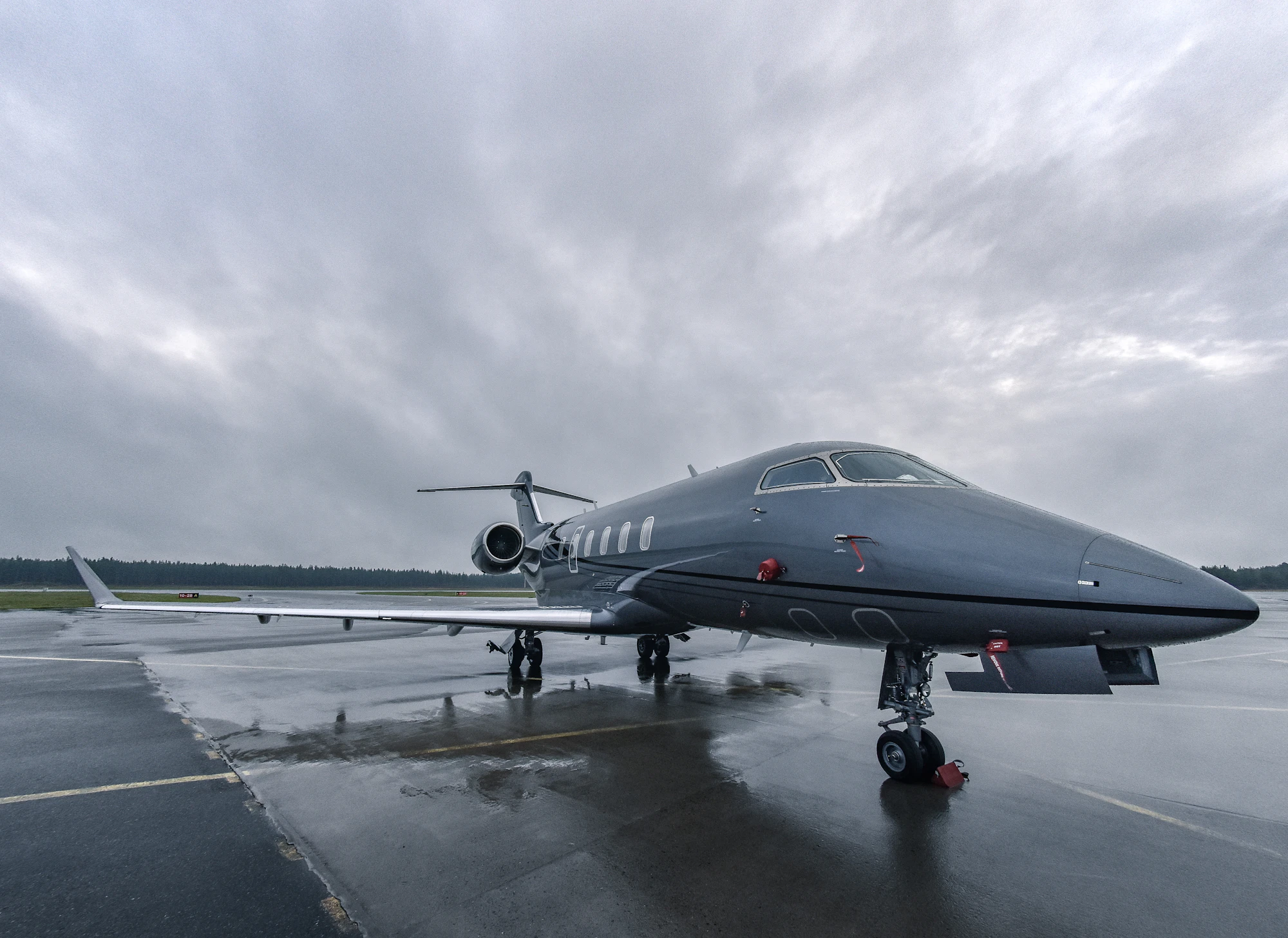 A super midsize business jet on a wet apron under grey skies, the class covered by super midsize jet charter cost