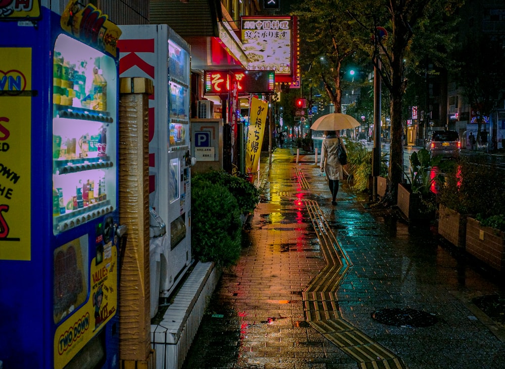 a city street at night with a person holding an umbrella