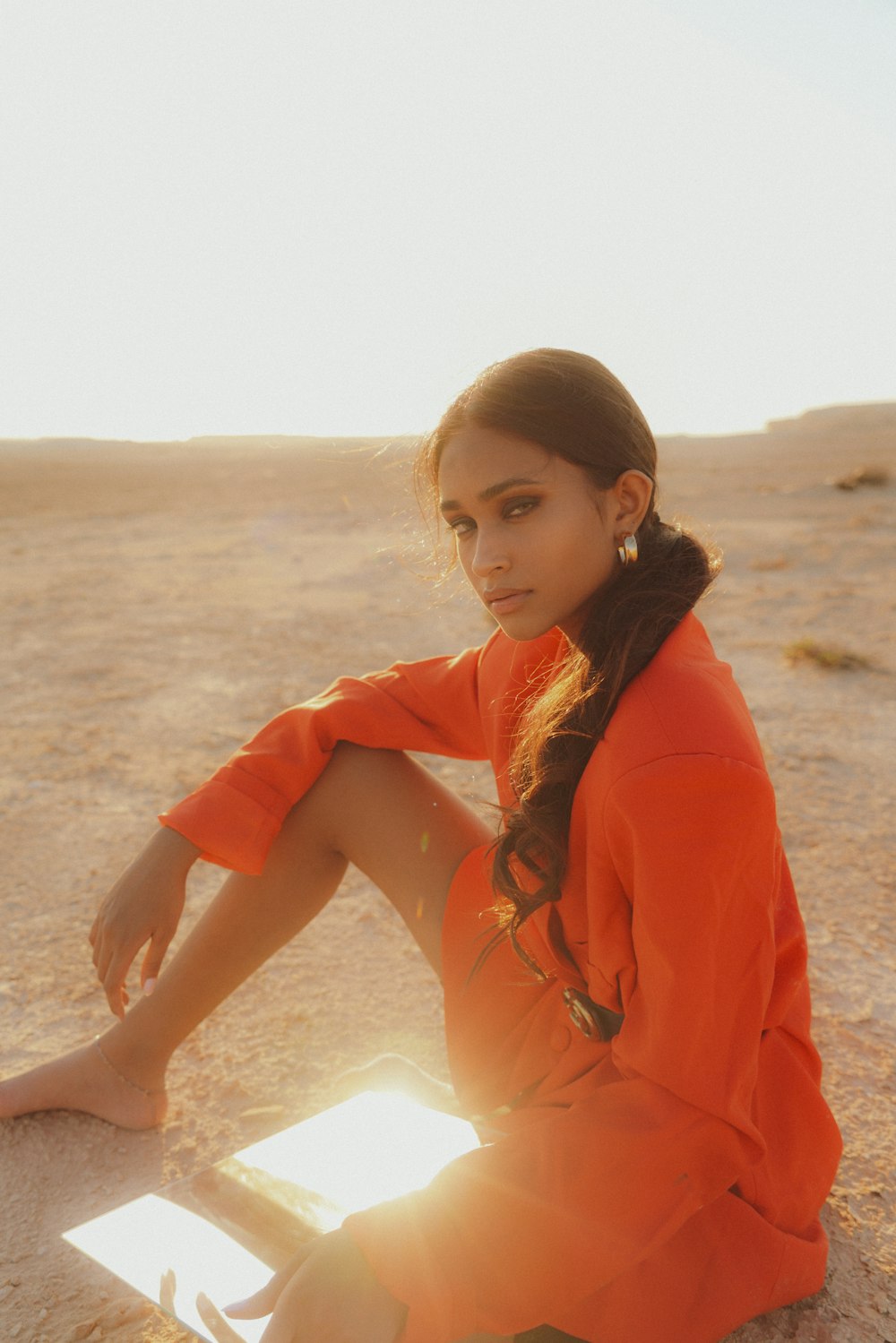 a woman sitting on the ground in the desert