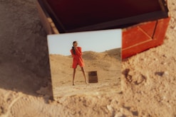 a woman in a red dress standing in the sand