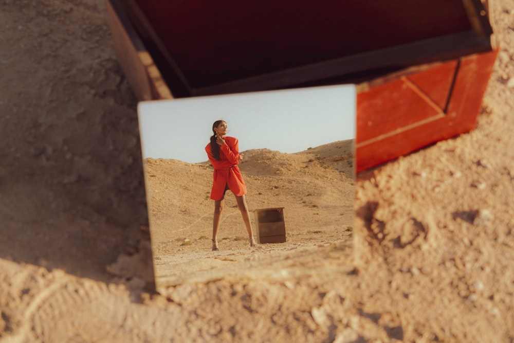 a woman in a red dress standing in the sand