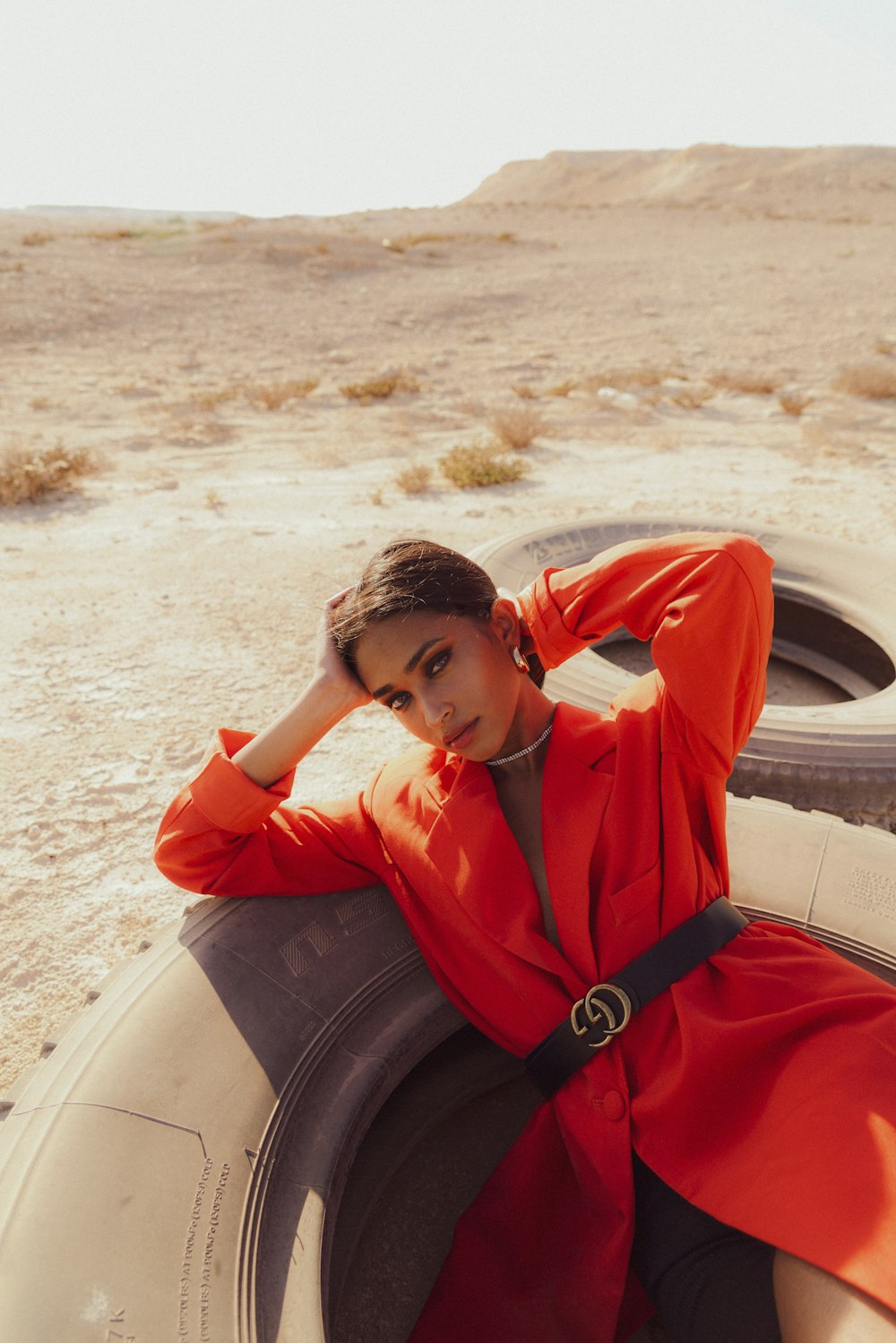 a woman sitting on top of a tire in the desert