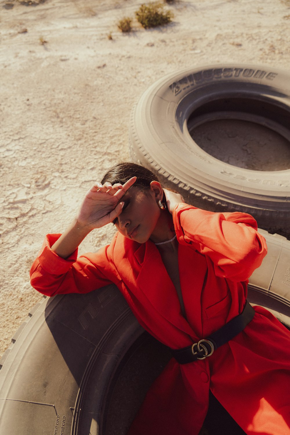 a woman sitting on top of a tire in the desert