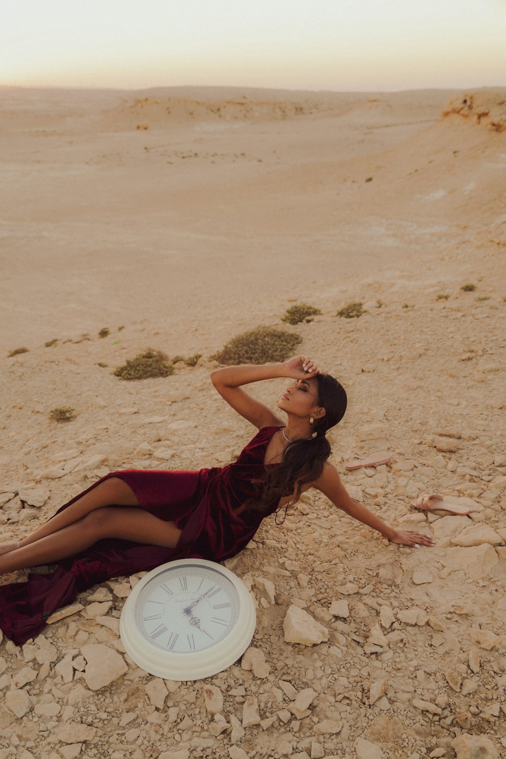 a woman laying on the ground next to a clock