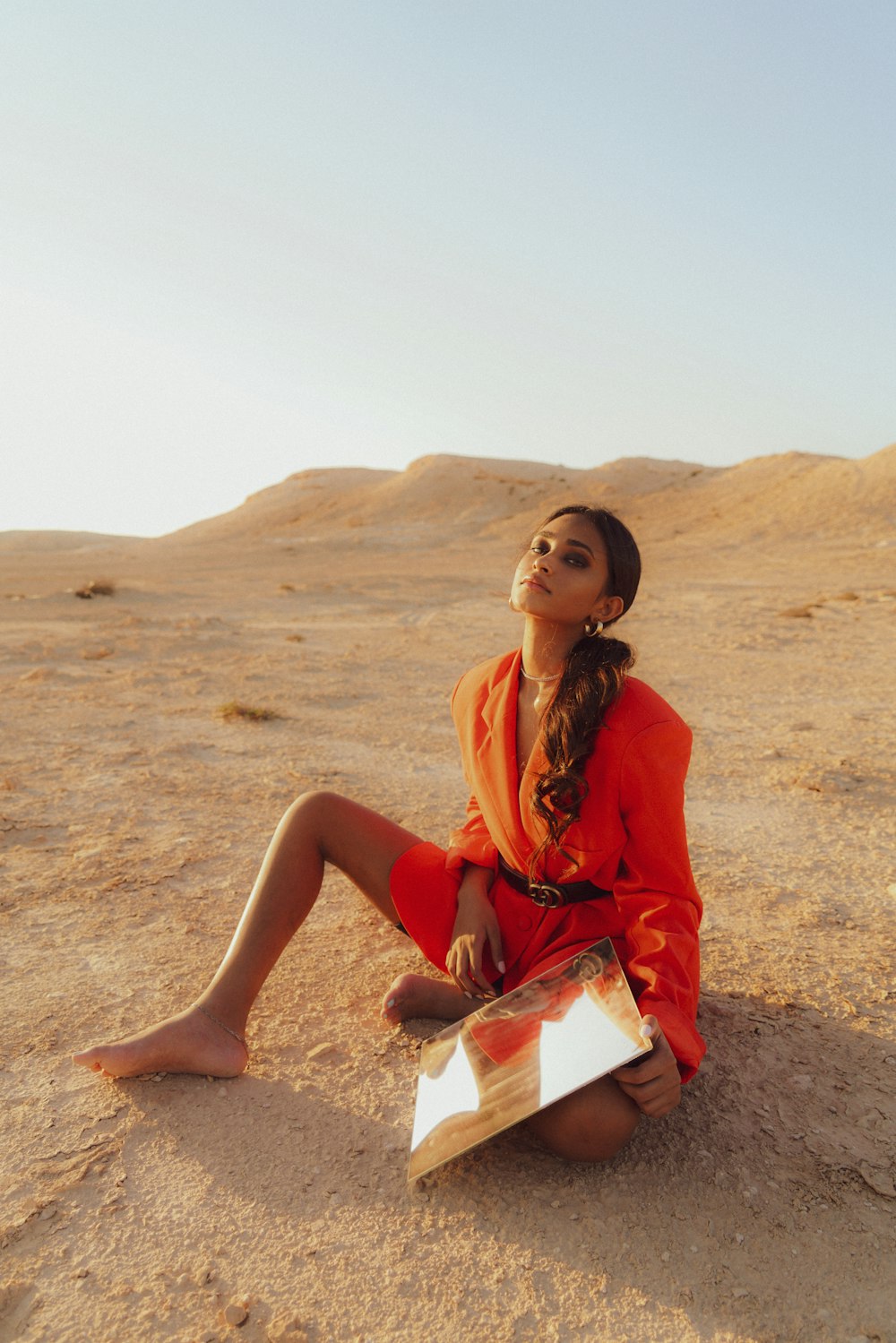 a woman sitting in the sand with a book