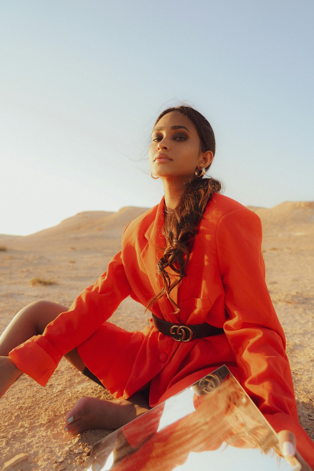 a woman in an orange dress sitting in the desert