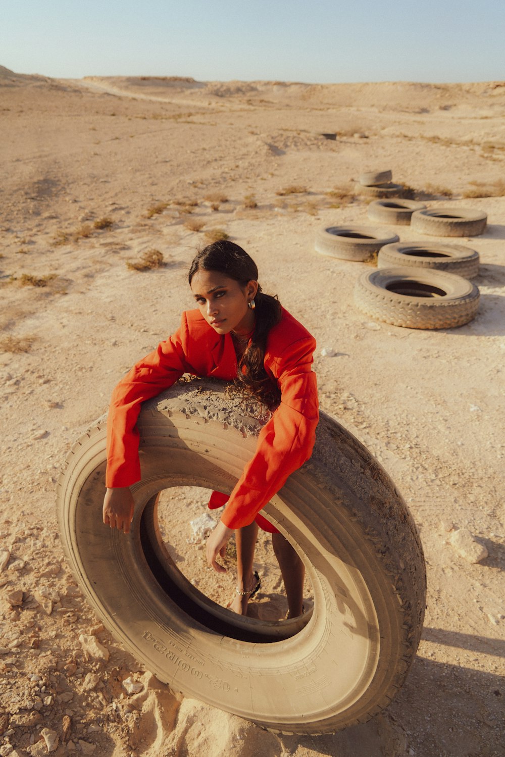 a woman sitting on top of a tire in the desert