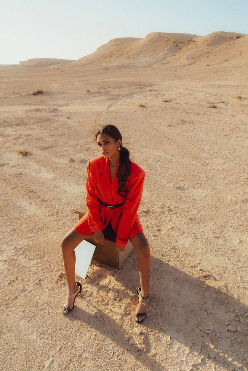 a woman in a red suit sitting in the desert