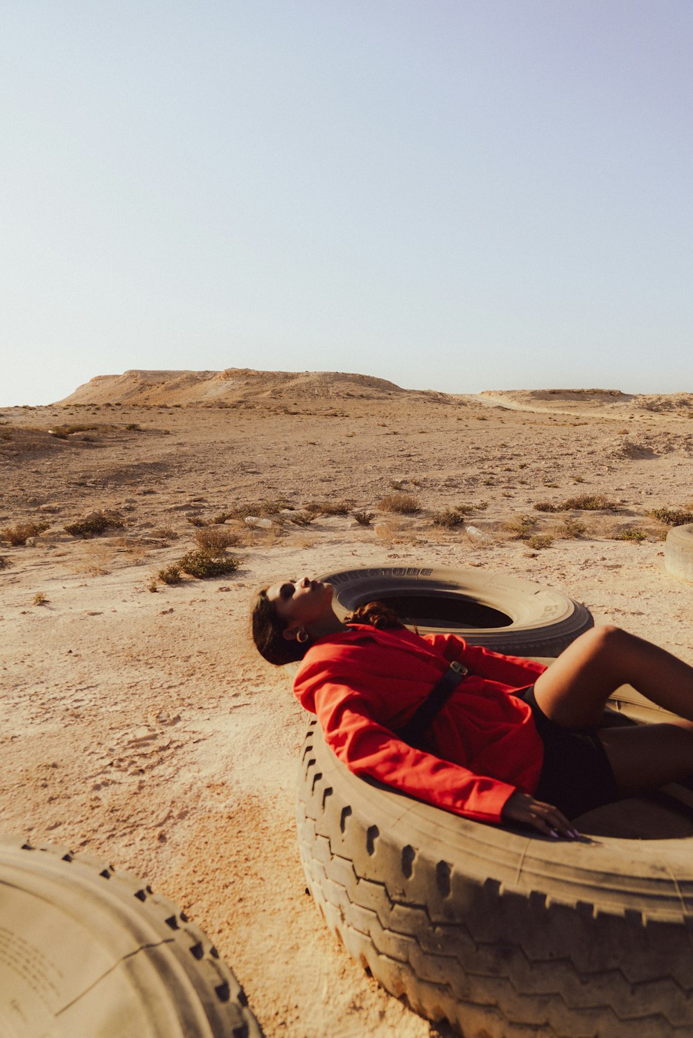 a man laying on top of a tire in the desert