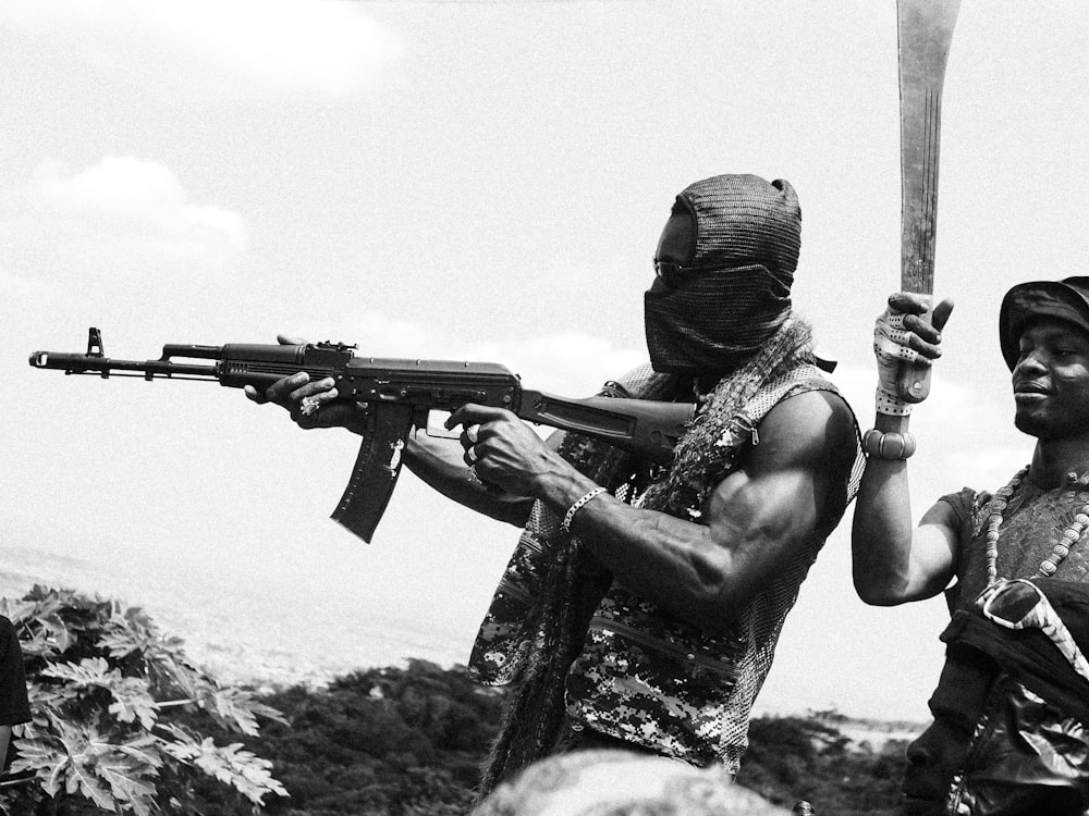 a man holding a rifle next to another man