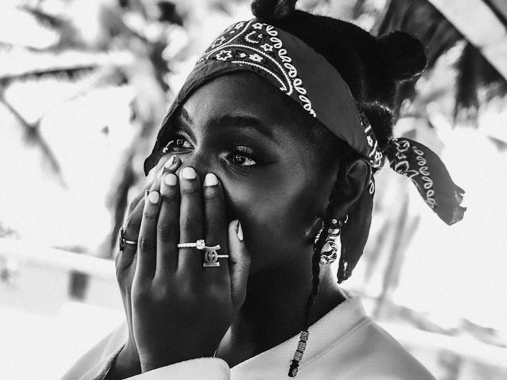 a black and white photo of a woman covering her mouth