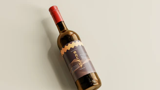 Elegant bottle of red wine with a dark matte background and soft golden lighting