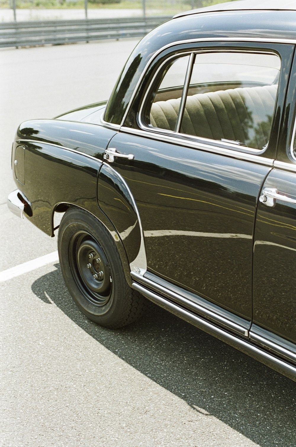 an old black car parked in a parking lot