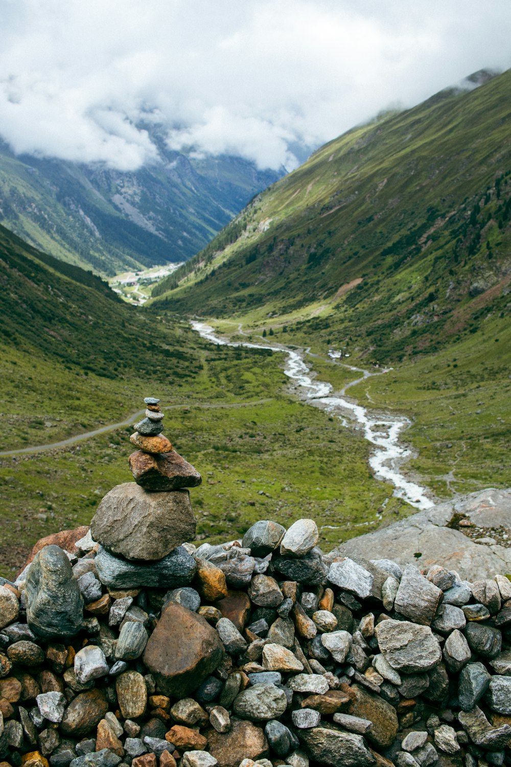 a pile of rocks sitting on top of a lush green hillside