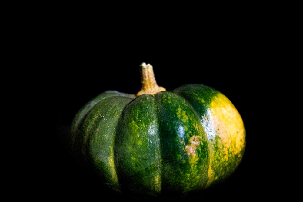 a group of green and yellow gourds on a black background