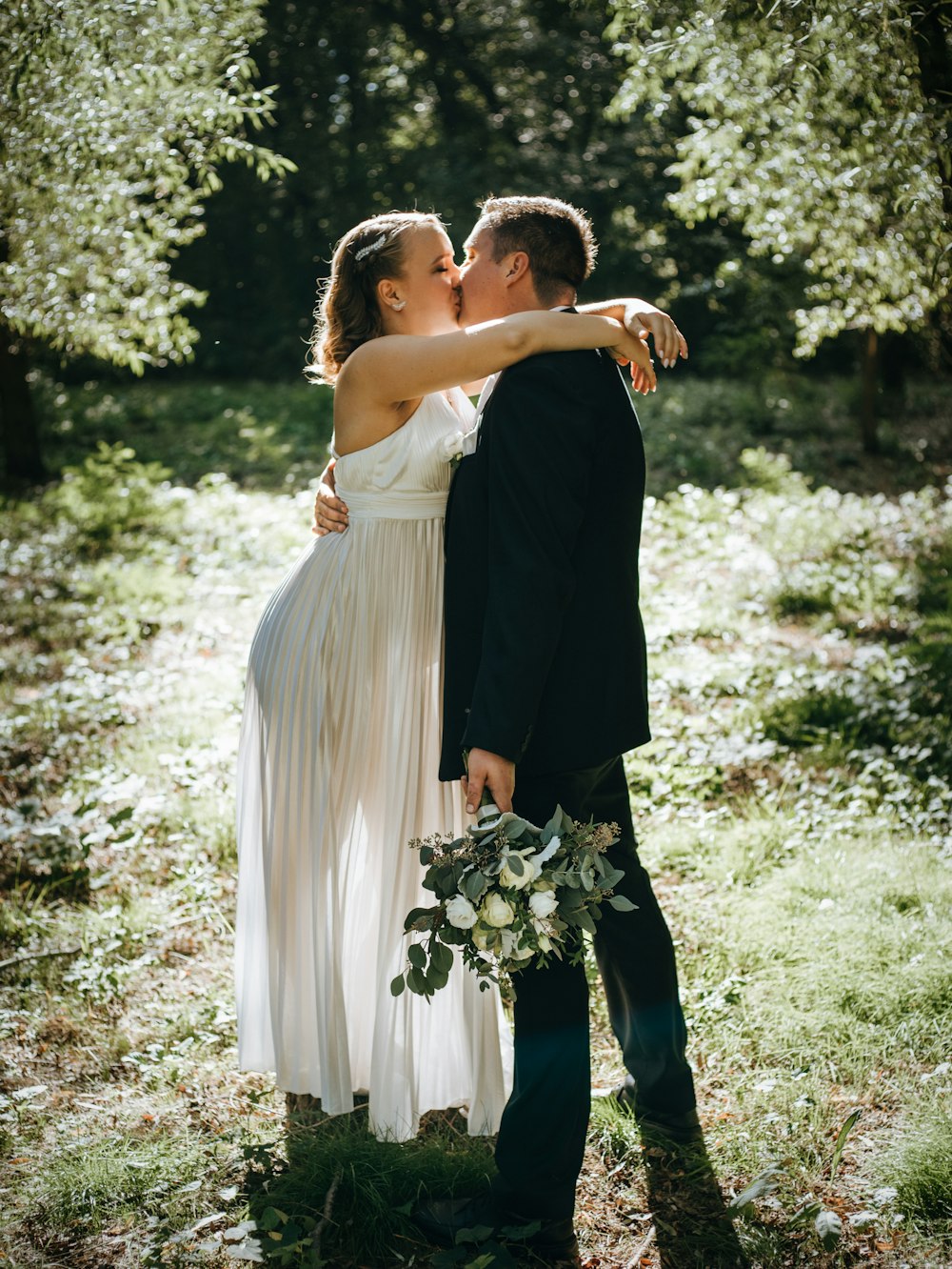 a bride and groom kissing in the woods