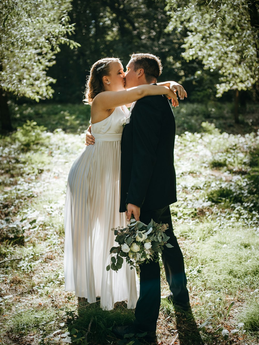 Una sposa e uno sposo che si baciano nel bosco