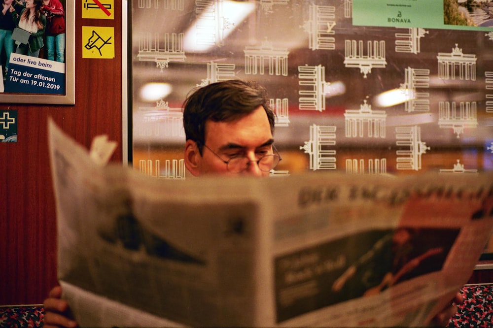 a man reading a newspaper in front of a window