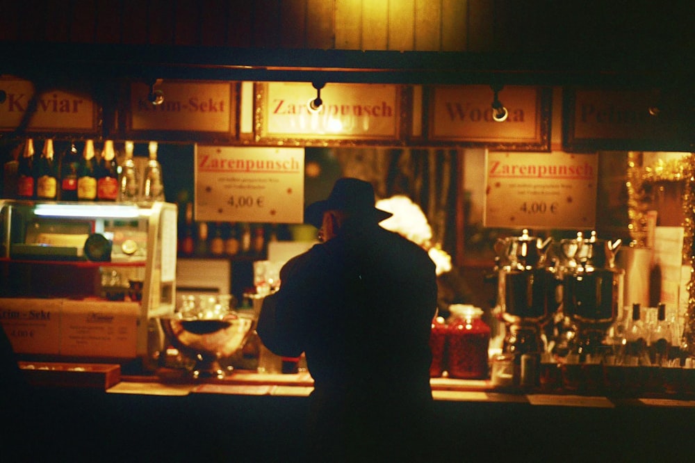 a man standing in front of a bar filled with liquor