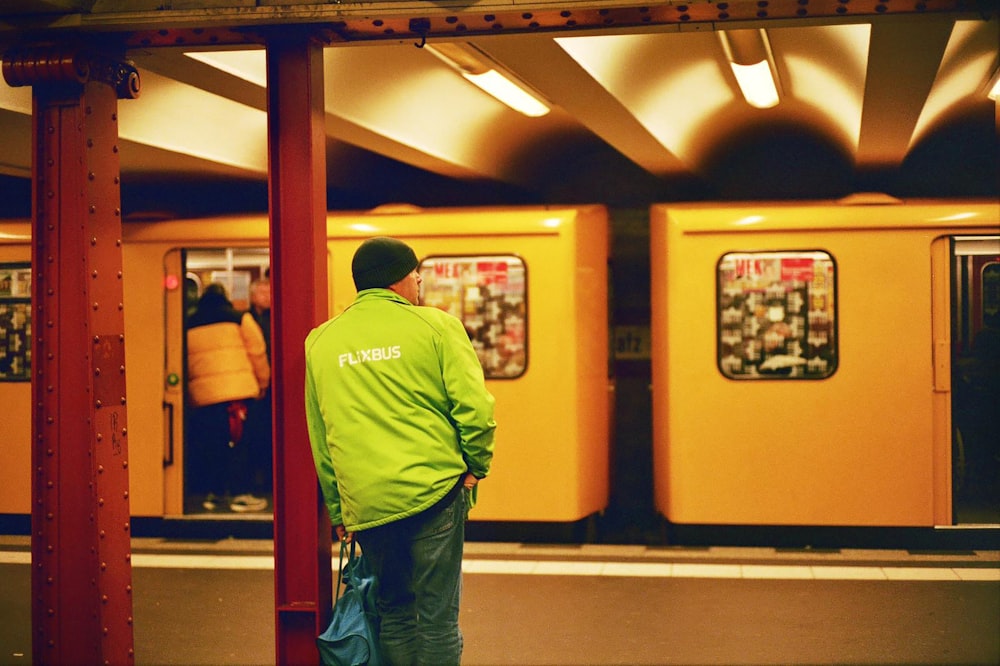a man in a green jacket waiting for a train