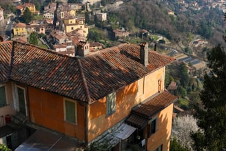 Sunset view over terracotta-colored houses nestled among green hills.