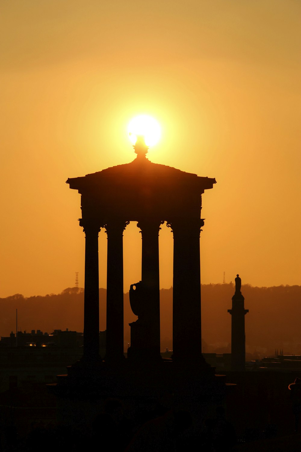 the sun is setting behind a building with pillars