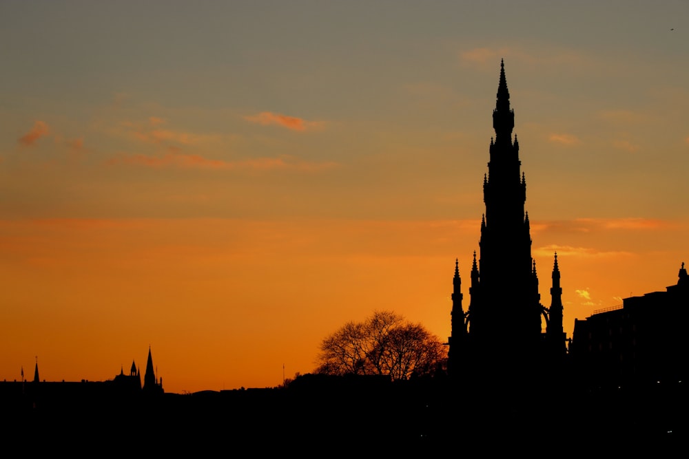 the silhouette of a church steeple against a sunset sky