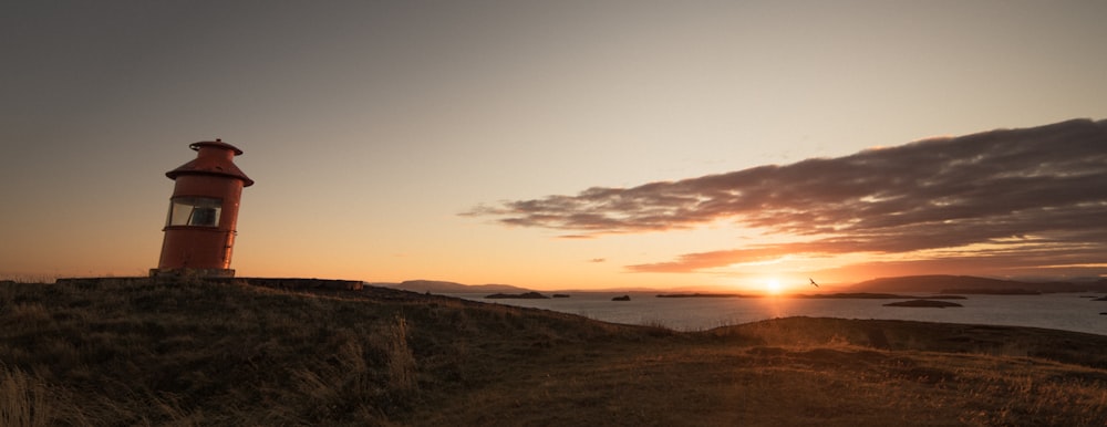 a red light house sitting on top of a hill