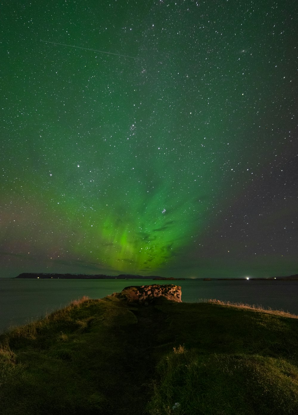 a green and purple aurora over a body of water