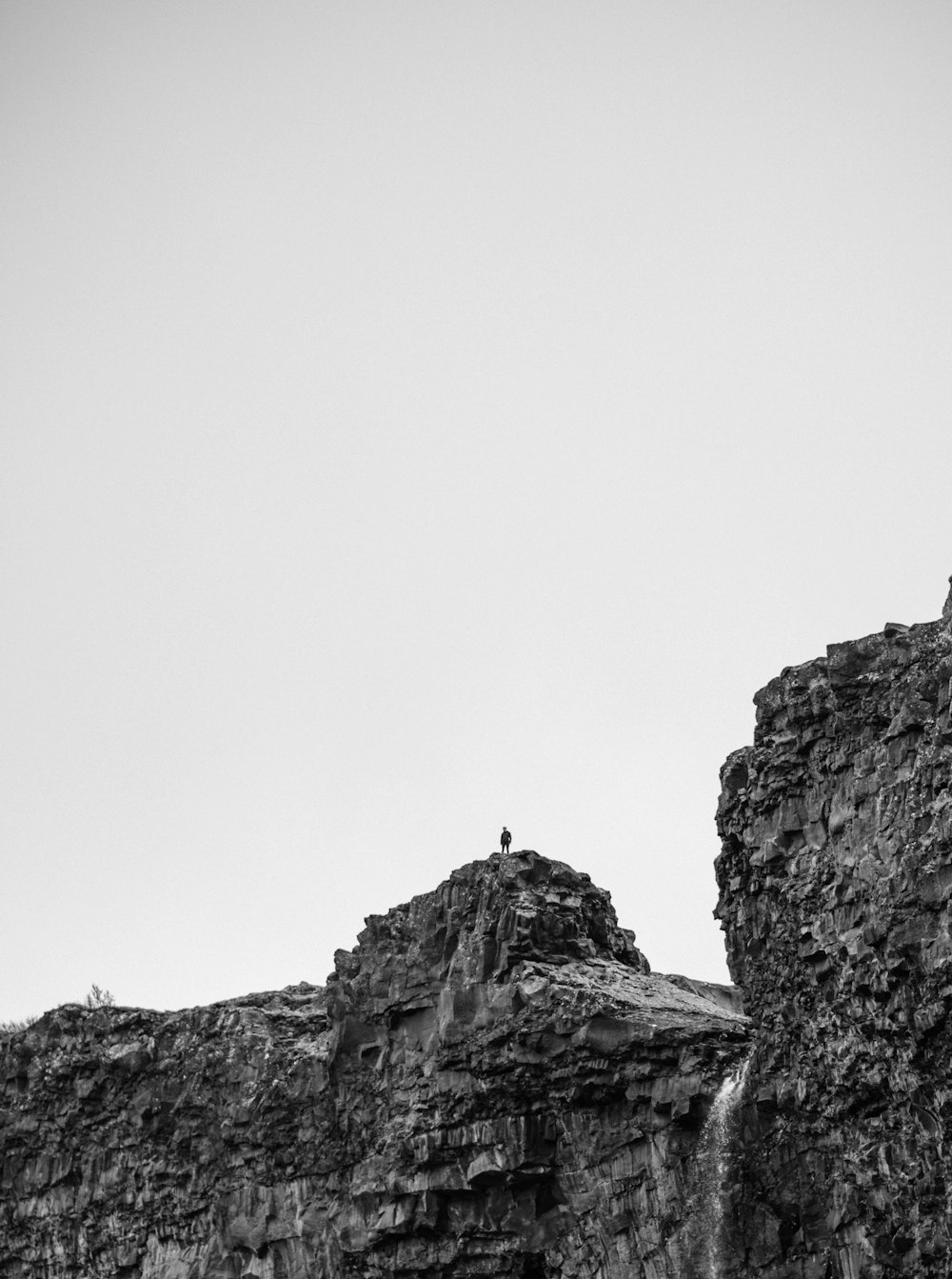 崖の上に立っている人の白黒写真
