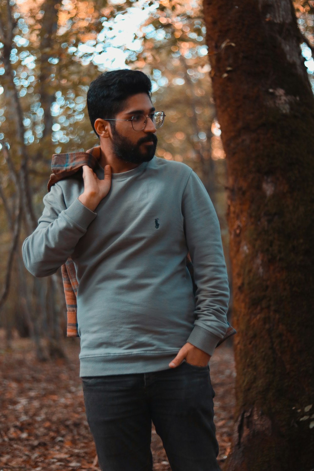 a man standing in the woods while talking on a cell phone