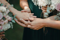 Pierre-Alain gently holding Cynthia’s hand with a backdrop of lilac draped fabric.